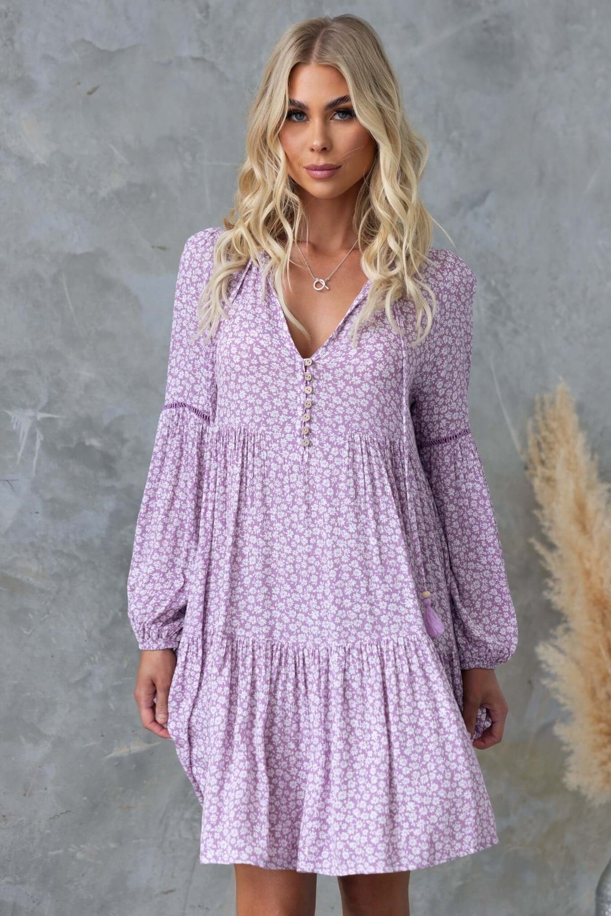 Fossa Dress featuring a V-neckline, tie detail, and button-up bust in a relaxed fit with floral pattern.