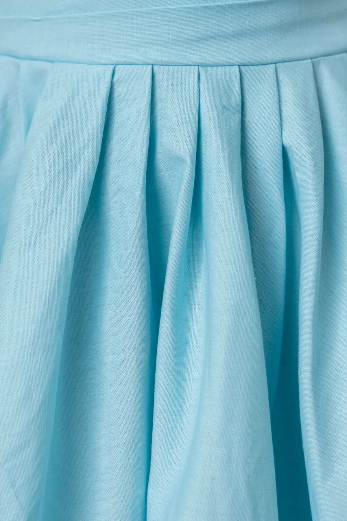 Close-up of a light blue maxi dress skirt featuring pleats for added style and texture.