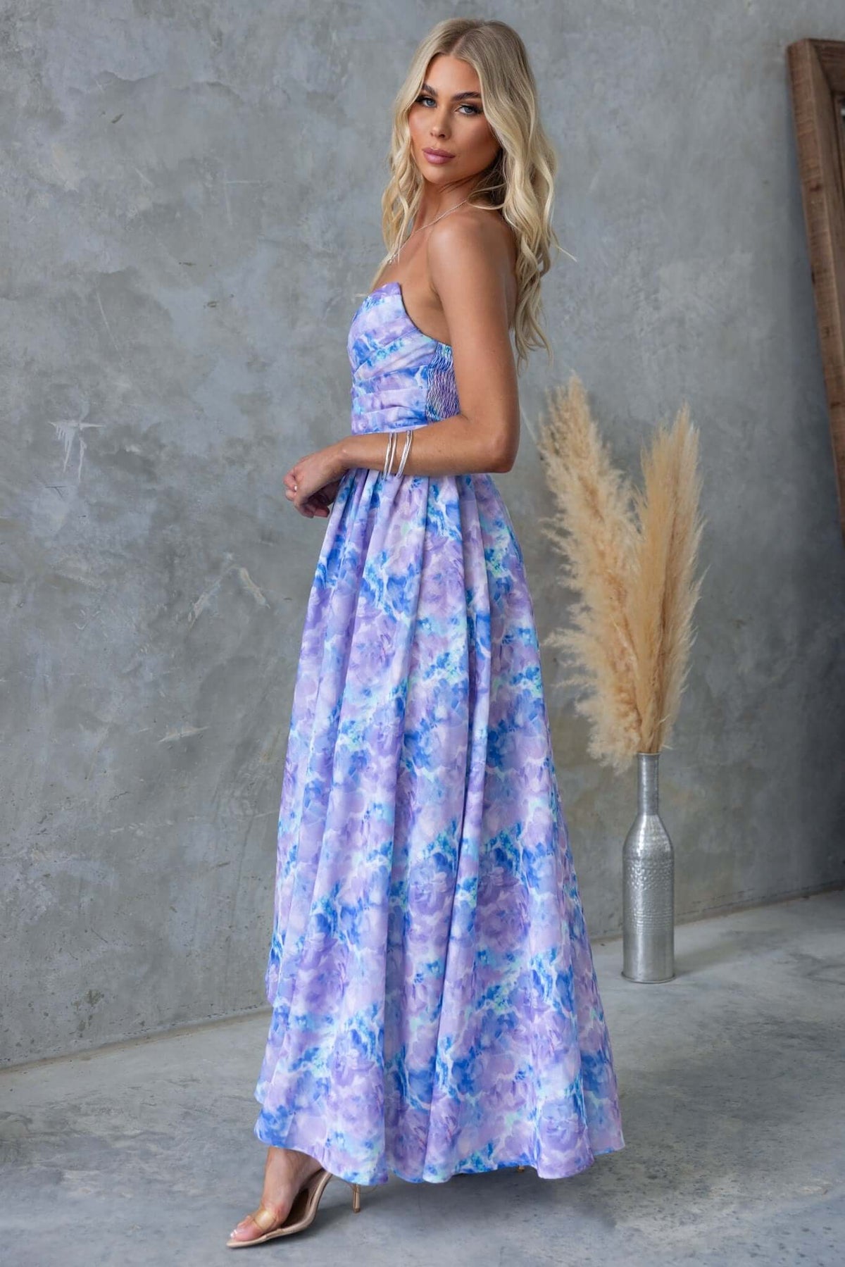 Model wearing the Kiss And Tell Maxi Dress, a strapless floral maxi with lightweight fabric in purple hues.