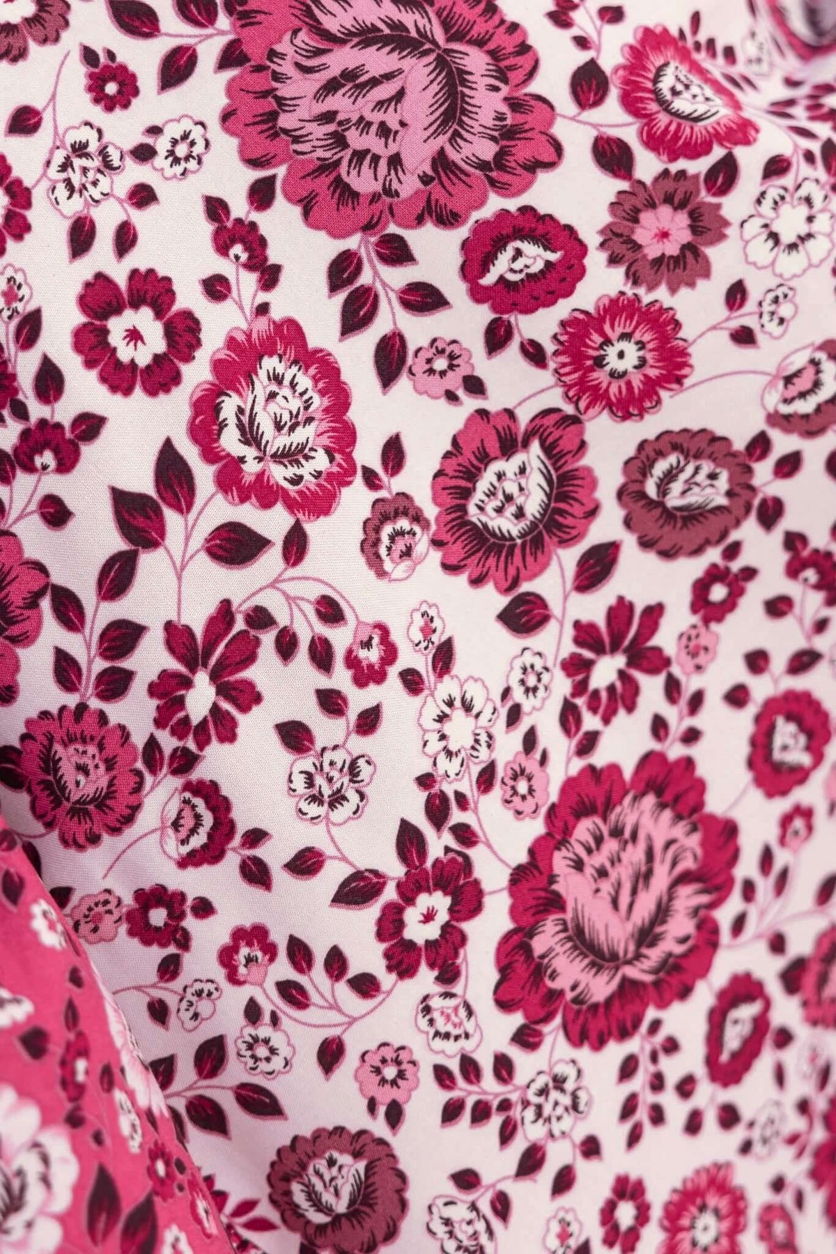 Close-up of floral patterned fabric in pink and burgundy, showcasing vibrant rose and flower designs.