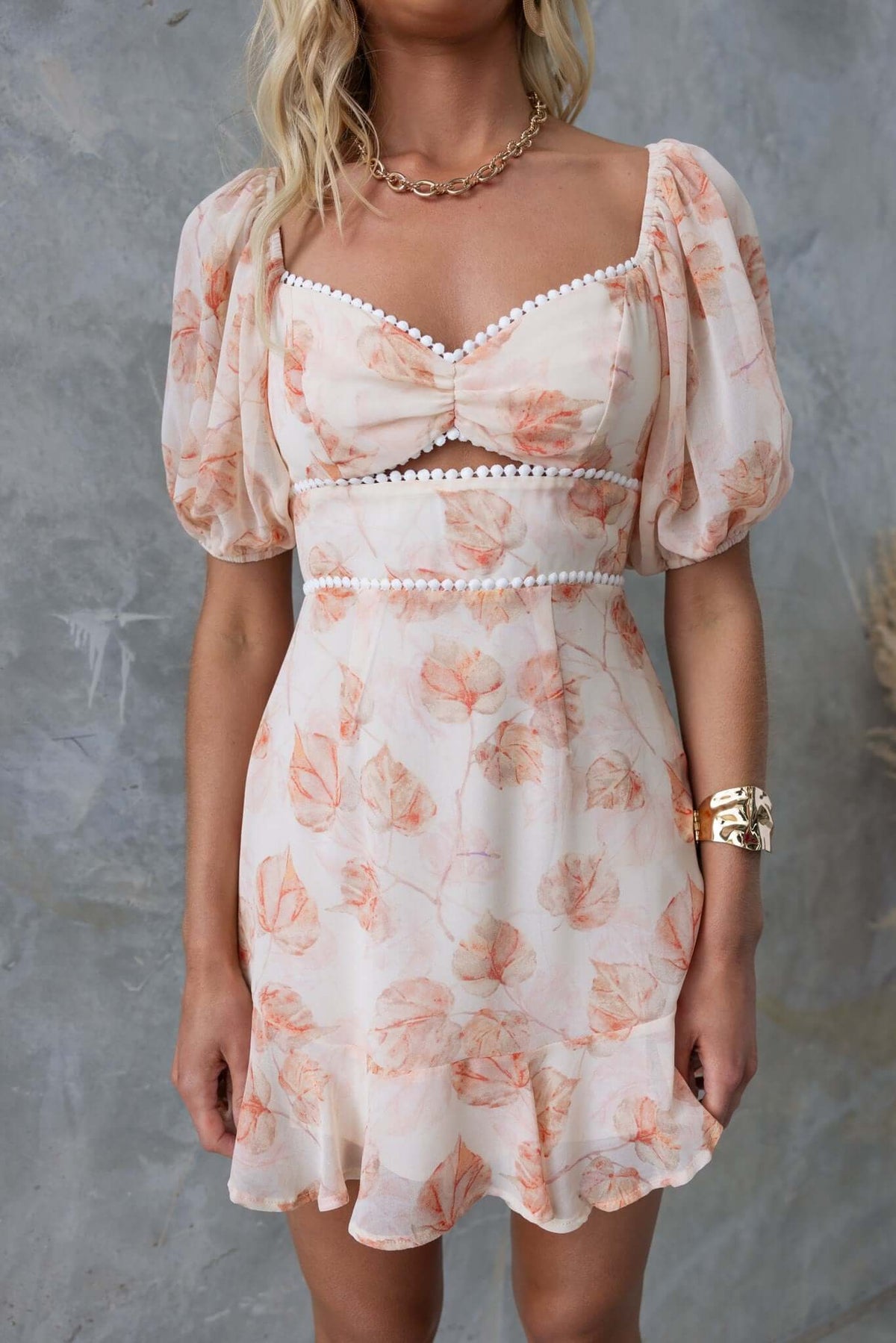 Model wearing the Star Drop Dress featuring floral chiffon, puff sleeves, keyhole under bust, and a delicate tie back.