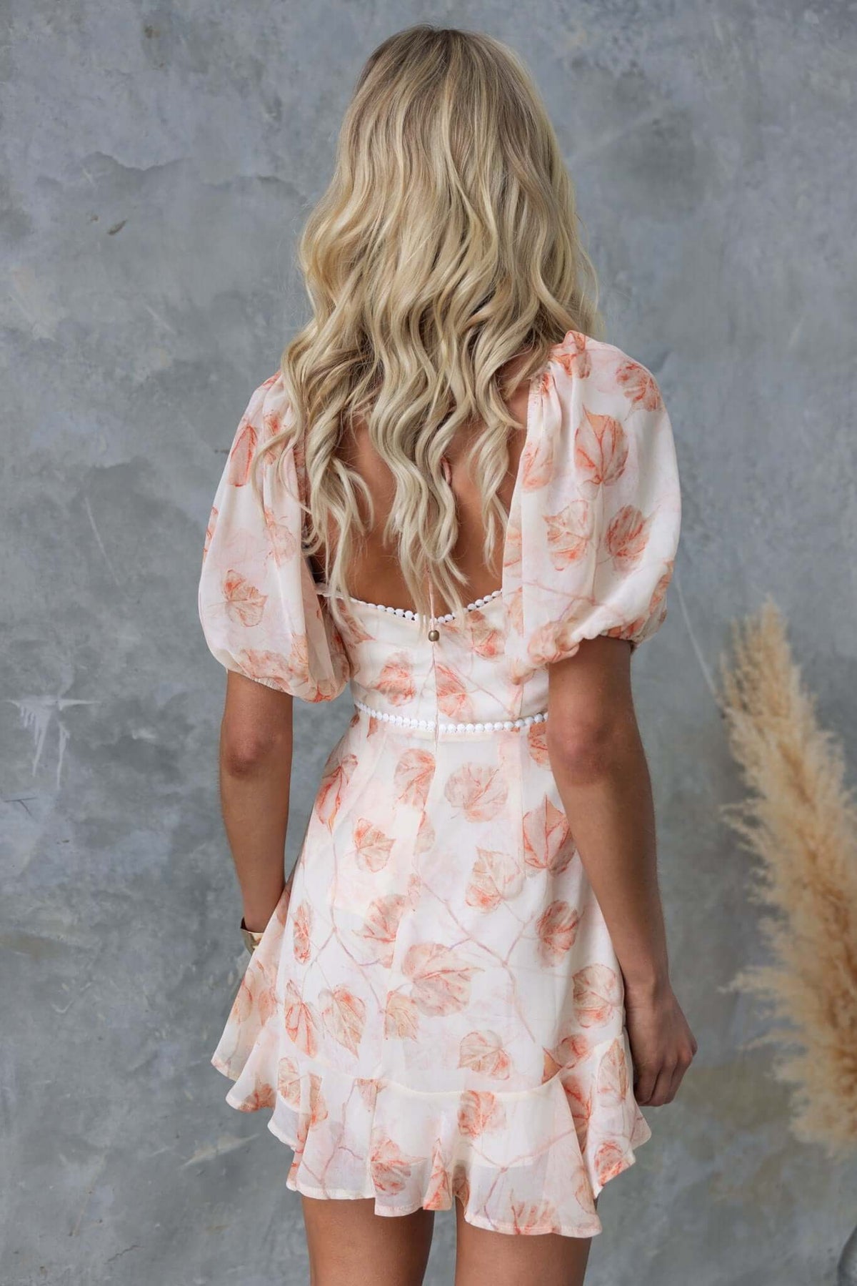 Back view of a model wearing the Star Drop Dress featuring floral patterns and puff sleeves.