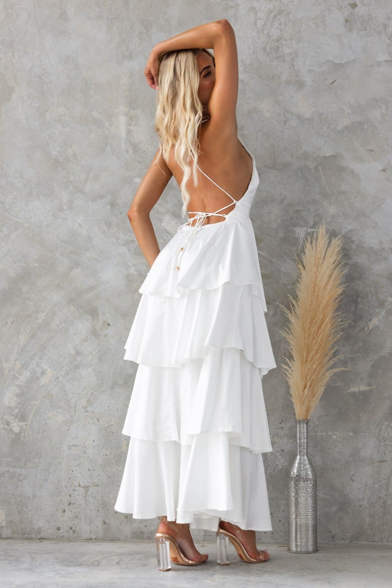 Back view of woman in white End Of Time Maxi Dress with ruffle skirt and lace-up detail.