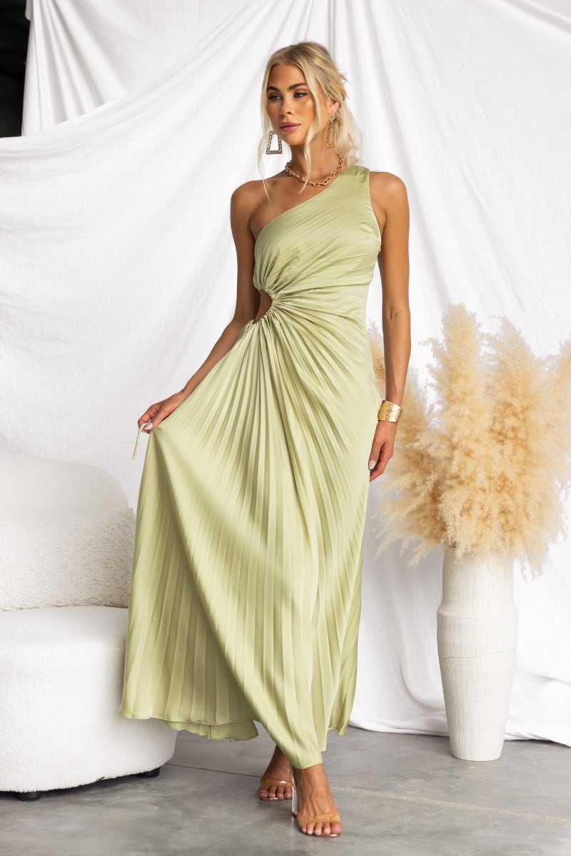 Model wearing a light green Ottile Maxi Dress with one-shoulder neckline and cut-out waist, styled with elegant accessories.