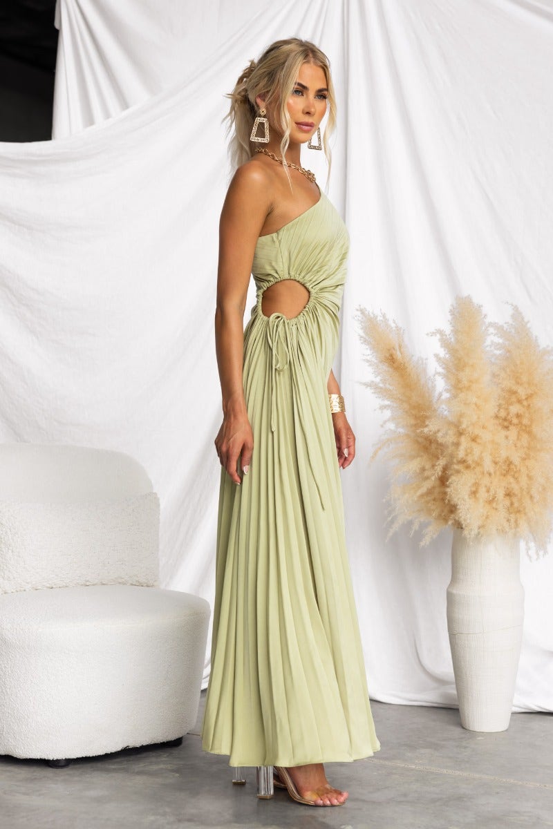 Model wearing a light green Ottile Maxi Dress with one-shoulder neckline and cut-out at waist.