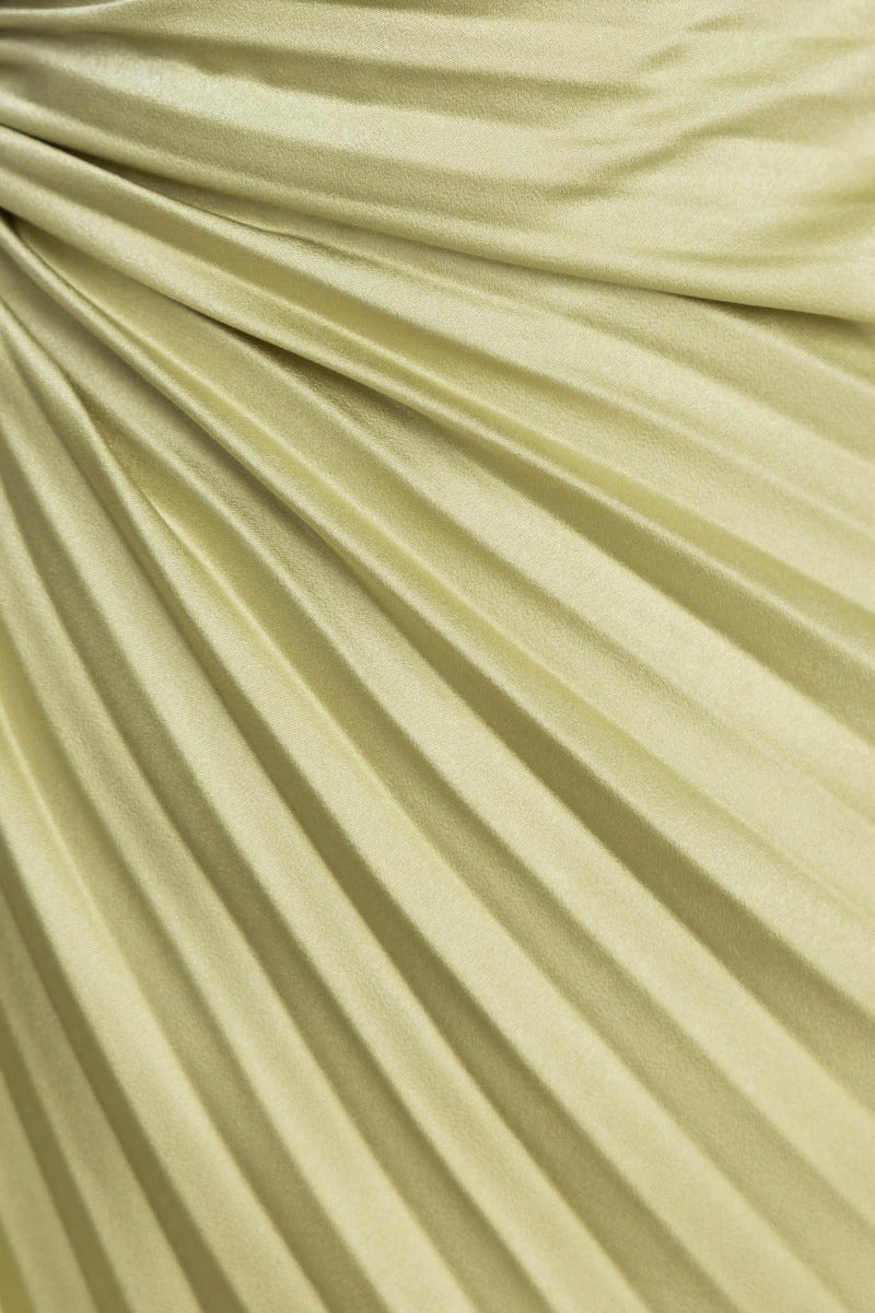 Close-up of pleated fabric in a soft yellow hue, showcasing texture and flow of the material.