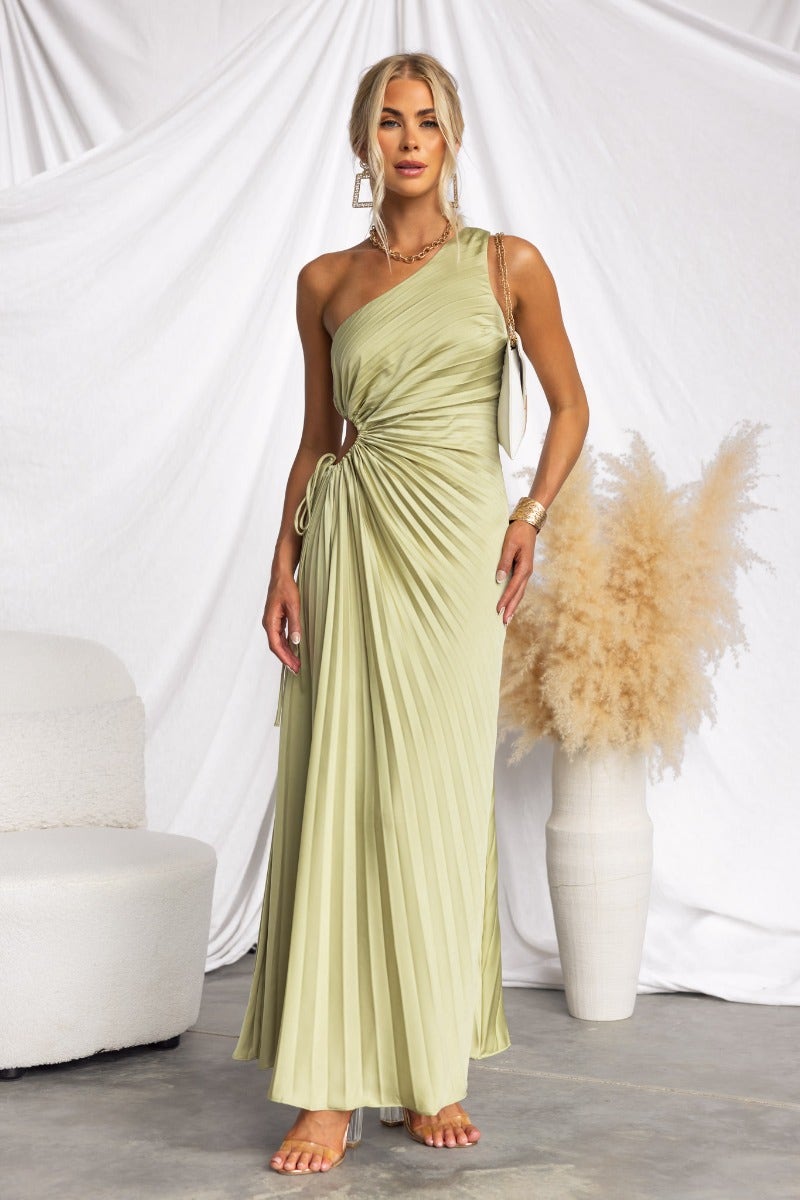Ottile Maxi Dress in light green with one-shoulder neckline, side cut-out, and pleated fabric, styled with accessories.