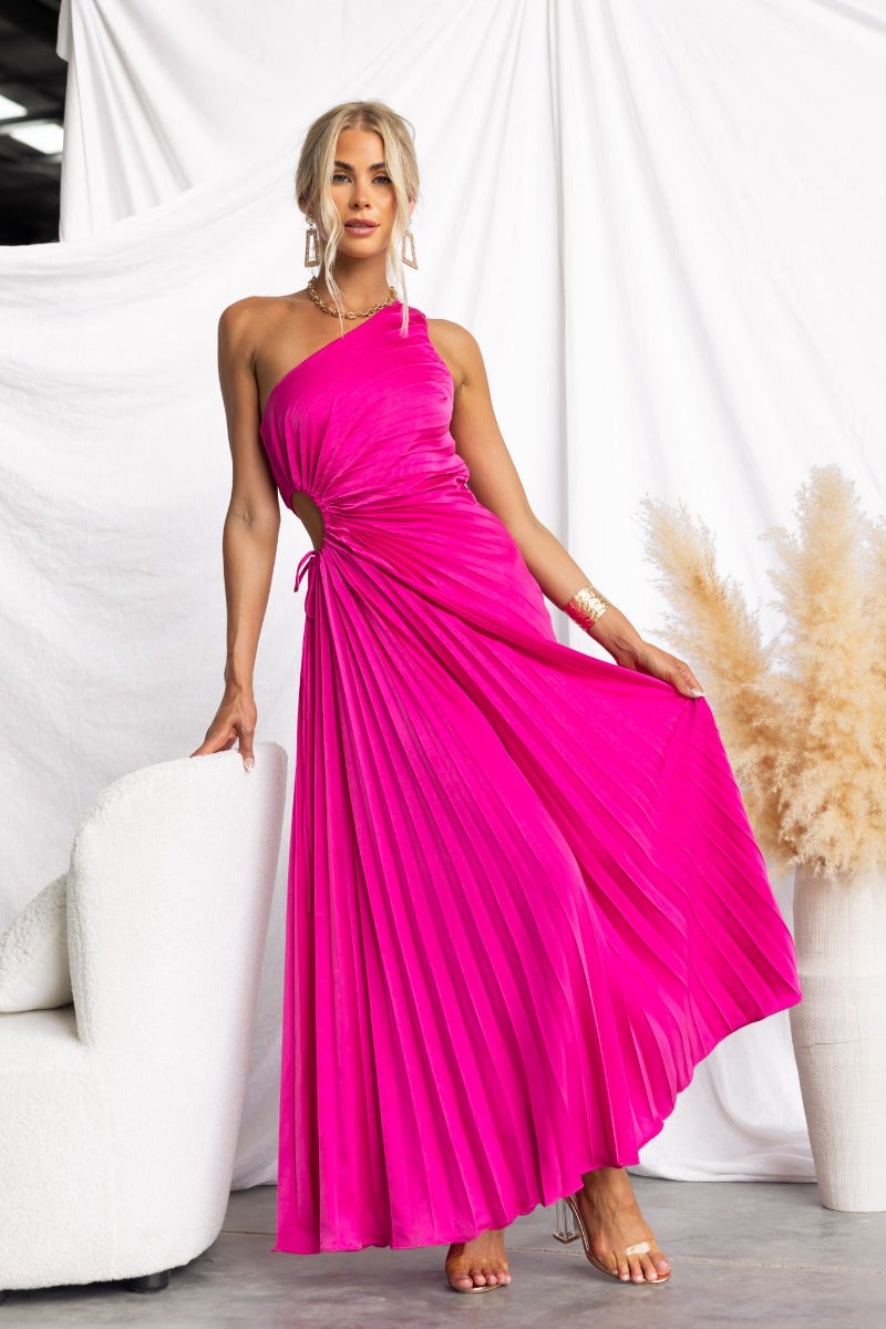 Model wearing a vibrant pink Ottile maxi dress with a one-shoulder neckline and pleated fabric.