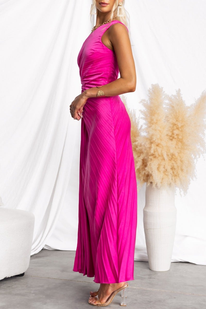 Model wearing a pink Ottile Maxi Dress with a one-shoulder neckline and side cut-out, showcasing accordion pleats.