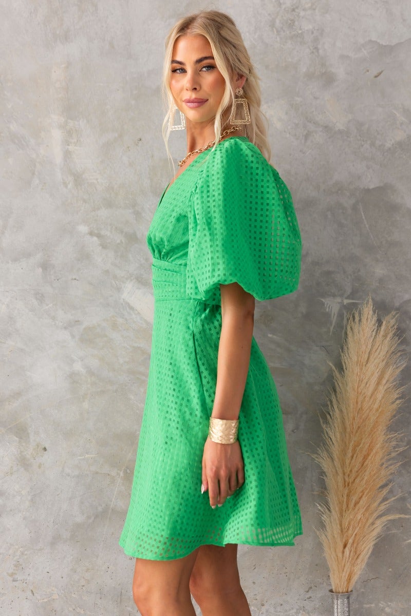 Lantier Dress in vibrant green with V-neckline and puff sleeves, styled for a chic summer look.