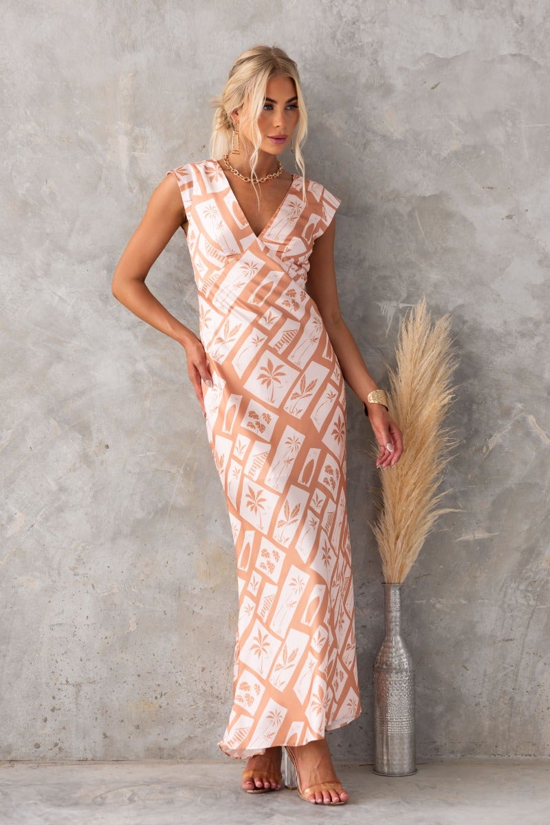 Model wearing a floral print Veneline maxi dress with a V-neckline and cap sleeves against a textured background.