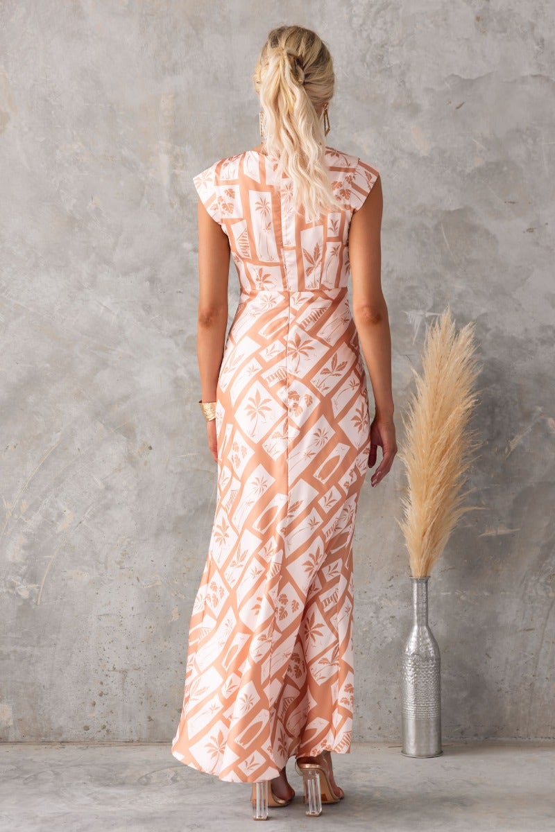 Back view of Veneline Maxi Dress featuring floral print, cap sleeves, and flowy silhouette, styled with a vase.