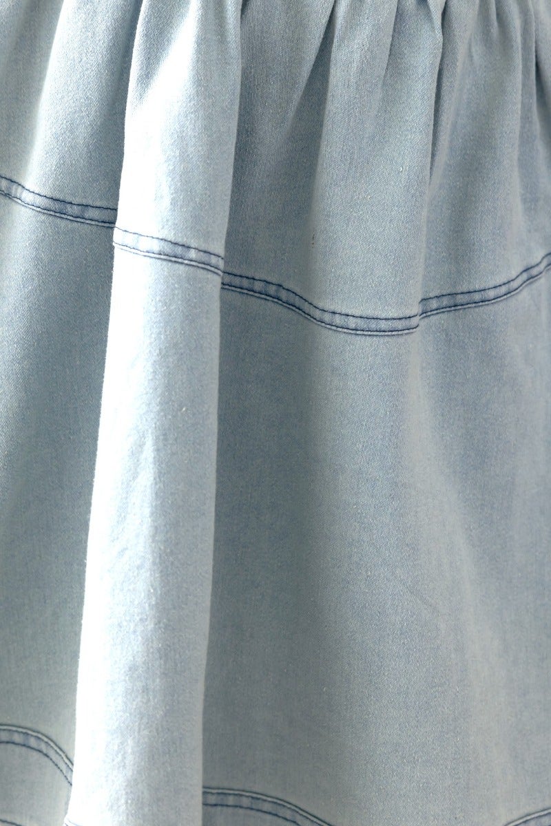 Close-up of the soft denim fabric of a strapless Never Again Denim Dress, showcasing pleats and stitching details.