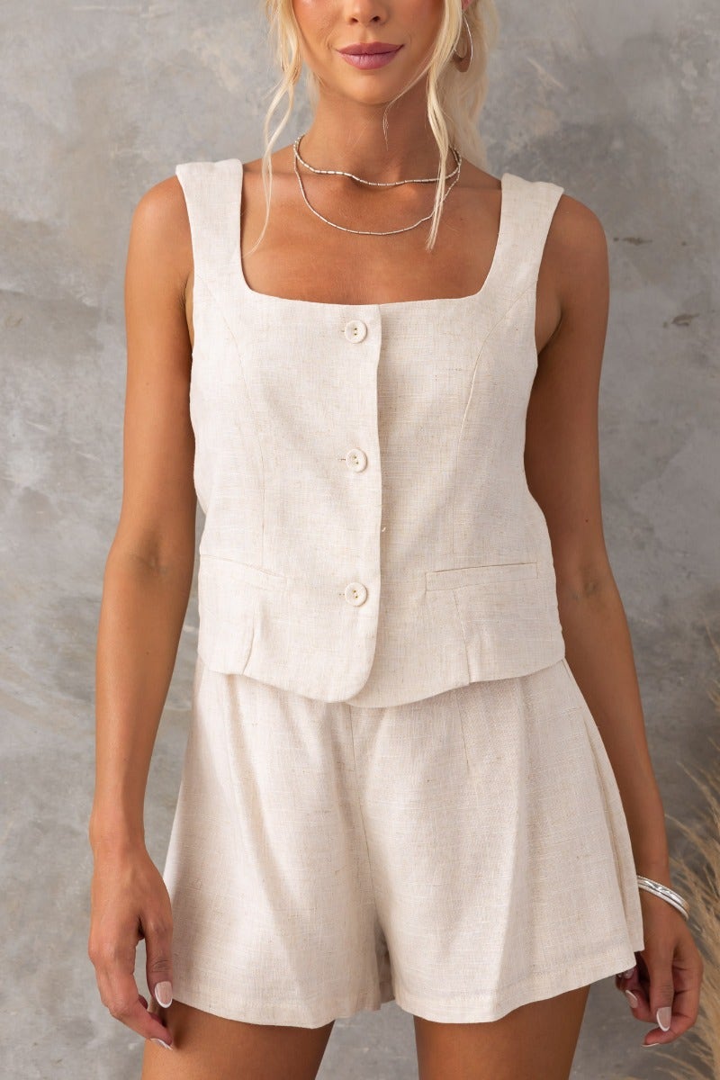 Woman in linen look beige Stand Still Shorts and matching buttoned top, showcasing a casual yet stylish summer outfit.