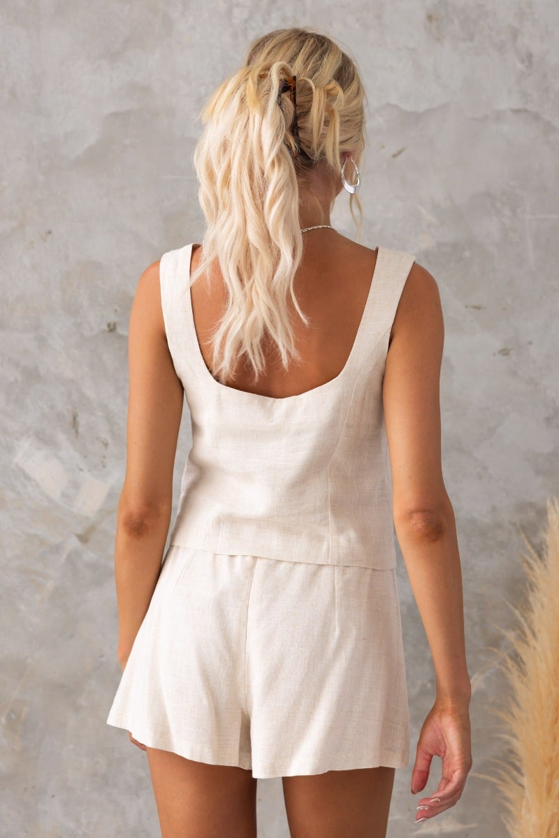Back view of a woman in a cream Stand Still Top with a relaxed fit, showing its linen look and feel.