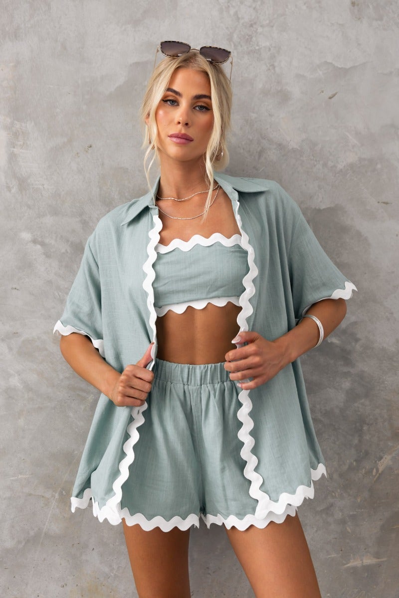 Model wearing Take It Easy Shirt with scalloped edges in muted green. Relaxed fit, perfect for summer wear.