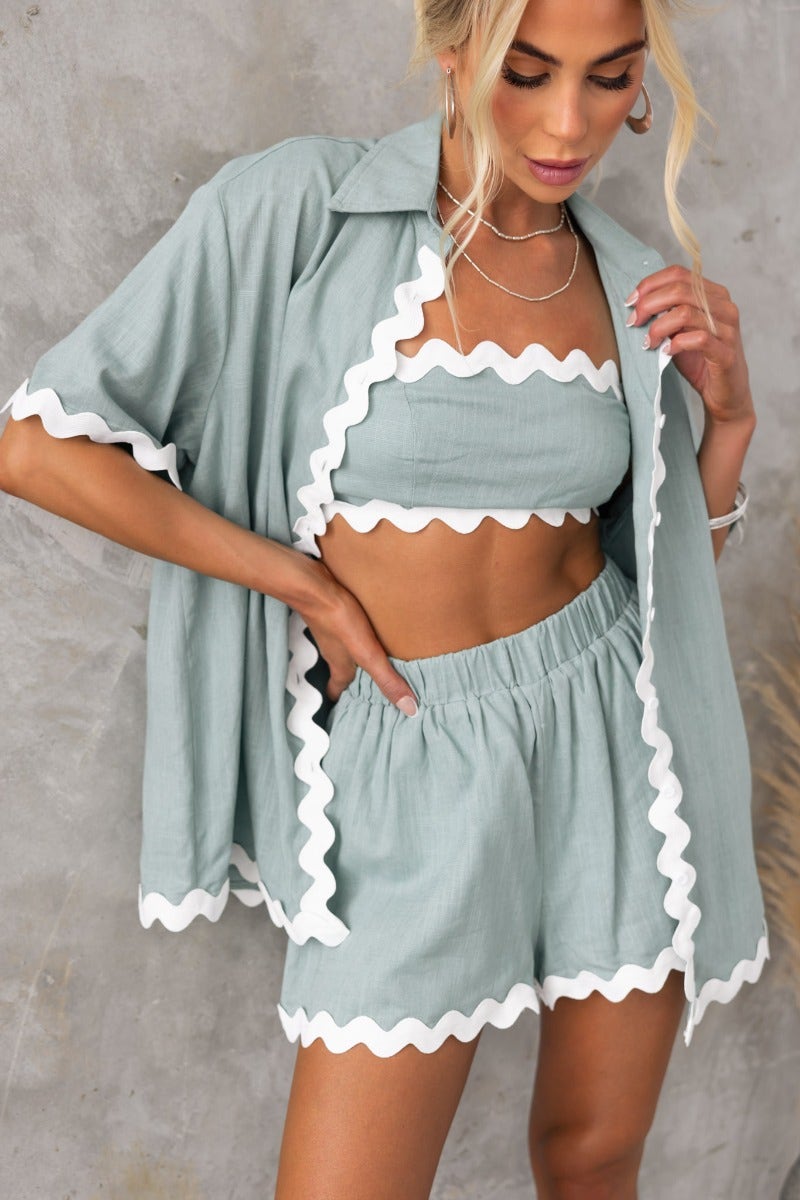 Woman wearing a mint green two-piece outfit with scalloped edges, featuring a cropped top and matching shorts.