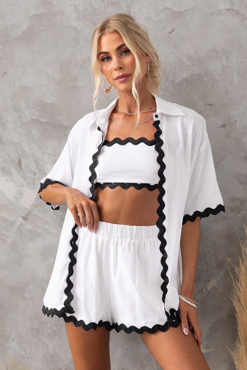 Stylish model in a white Take It Easy Shirt and matching shorts with black trim, showcasing a relaxed fit and casual summer vibe.