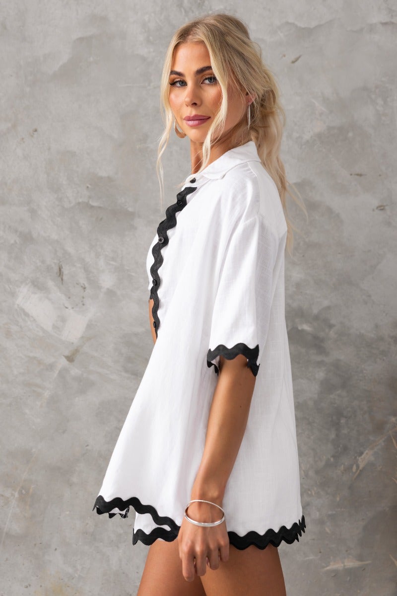 Take It Easy Shirt features a white button-up design with black ruffle trim, perfect for a relaxed fit casual look.