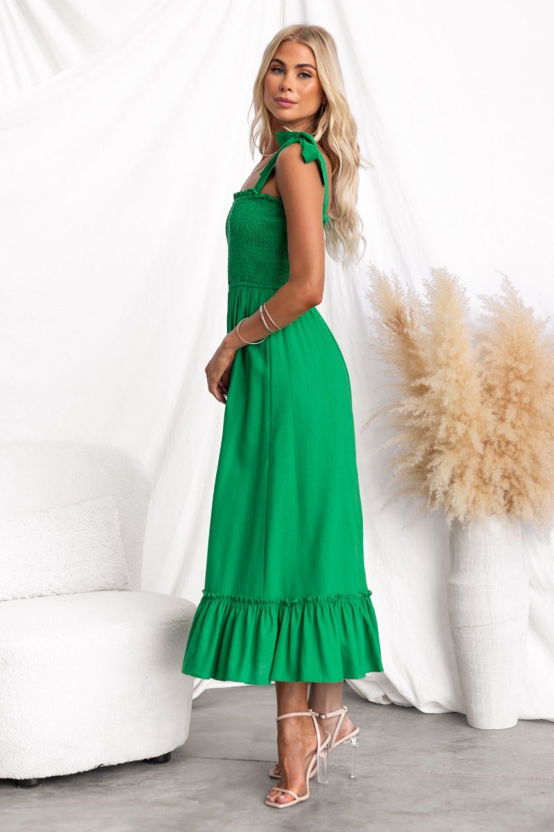 Qaniva Midi Dress in vibrant green with adjustable tie straps and ruffled hem, styled on model against soft backdrop.
