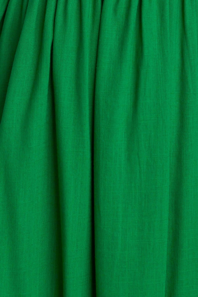 Close-up of green fabric showcasing the texture and drape of the rayon-linen blend in a midi dress.