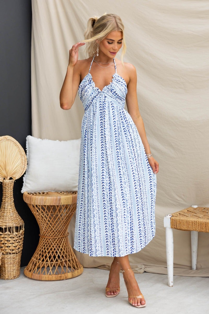 Stylish woman in abstract print Qano Midi Dress with adjustable tie back and pockets, showcasing a casual summer look.