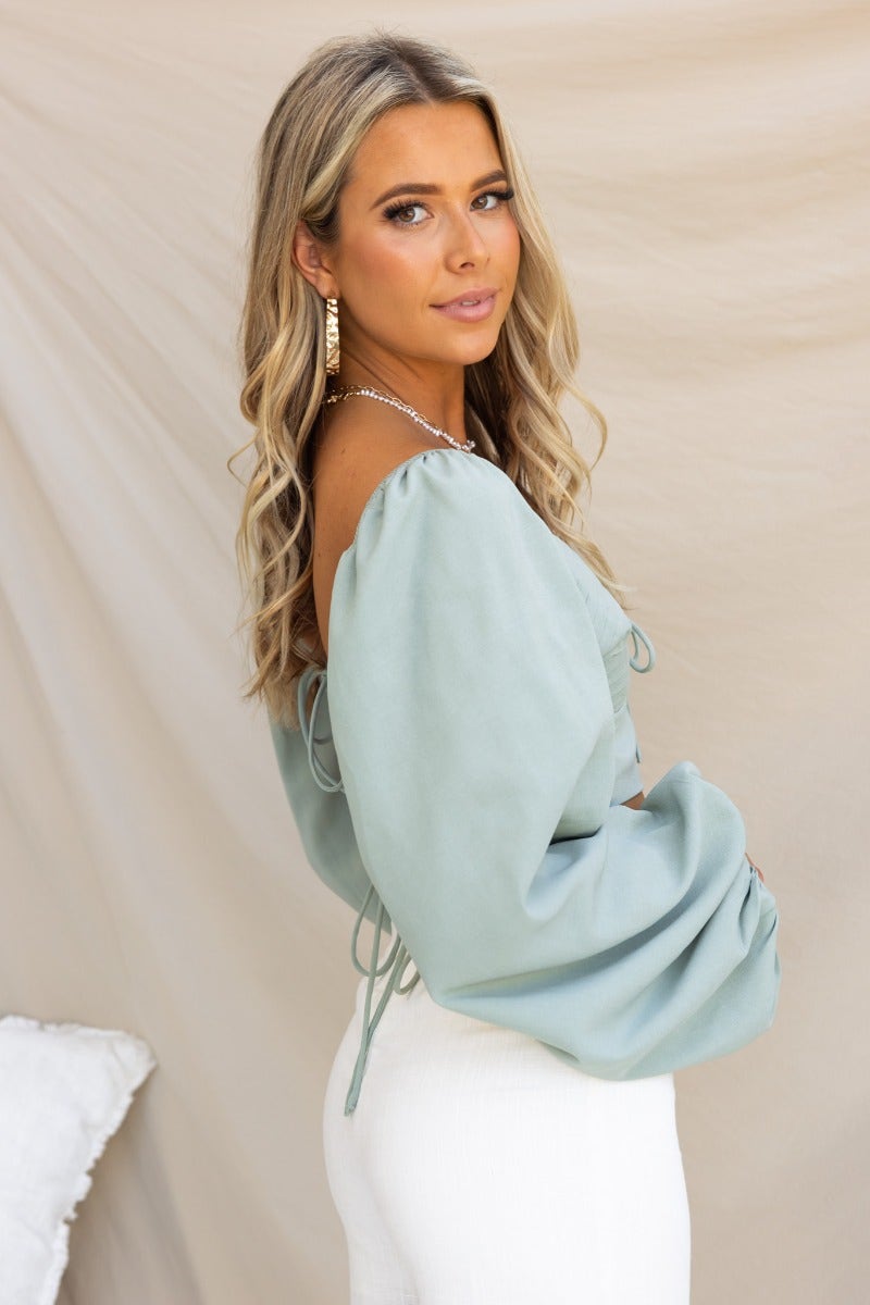 Model wearing the Flaria Top, featuring a sweetheart neckline and open back tie details in light blue.