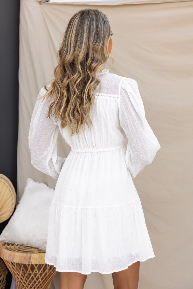 Back view of a model wearing a white Alita Dress with puff sleeves and an elastic waistband, showcasing its stylish design.
