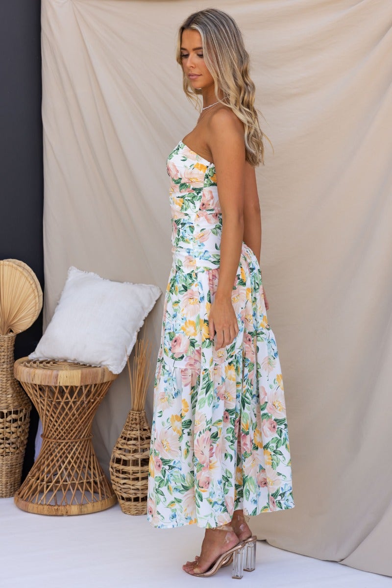 Woman wearing a floral strapless Blaine Maxi Dress, side view, showcasing the elegant style and mid-thigh lining.