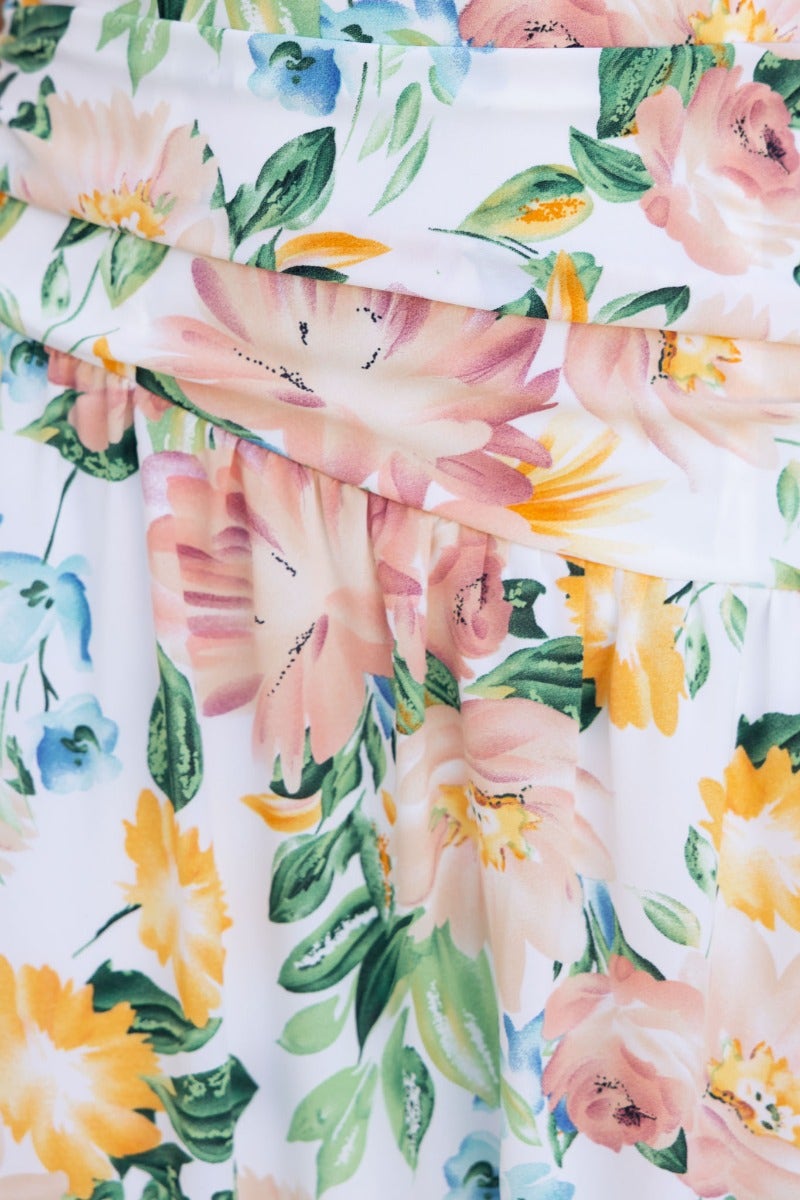 Close-up of floral pattern on the Blaine Maxi Dress featuring soft pink and yellow flowers against a white background.