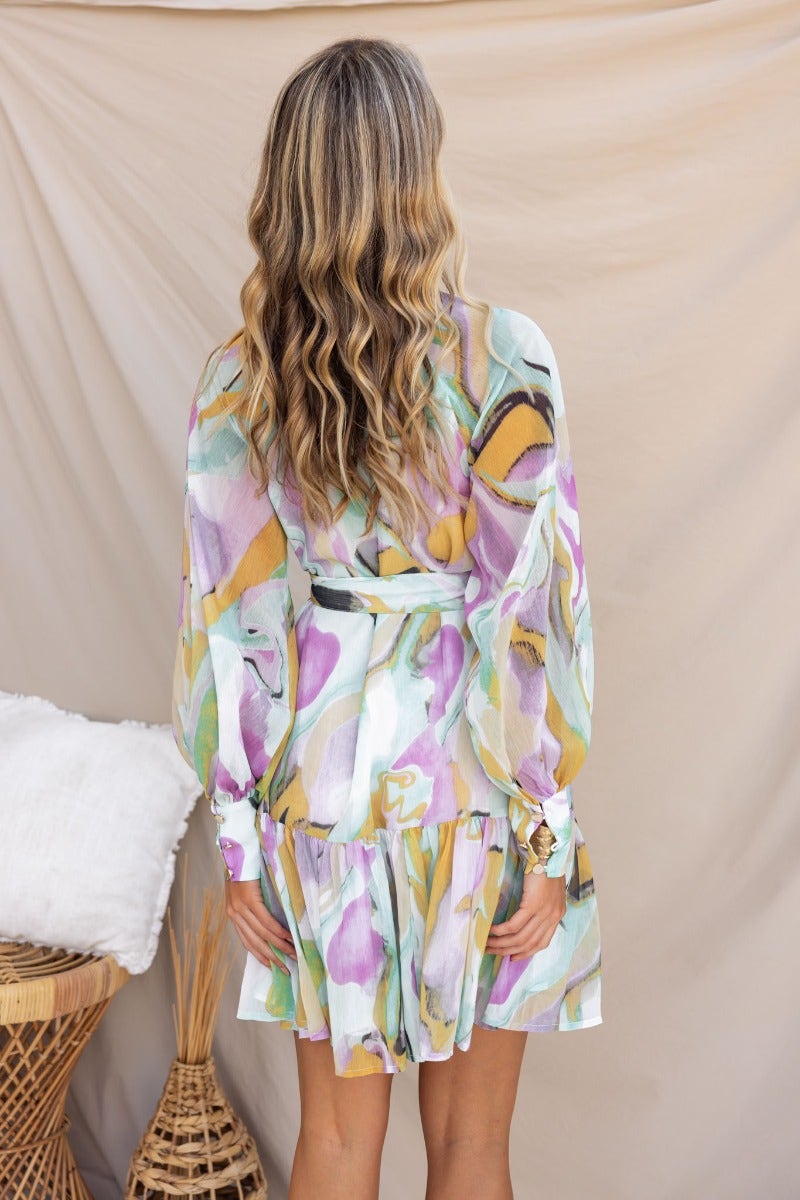 Back view of a woman in a multi-colour print Orazio Dress with a high neckline and removable belt.
