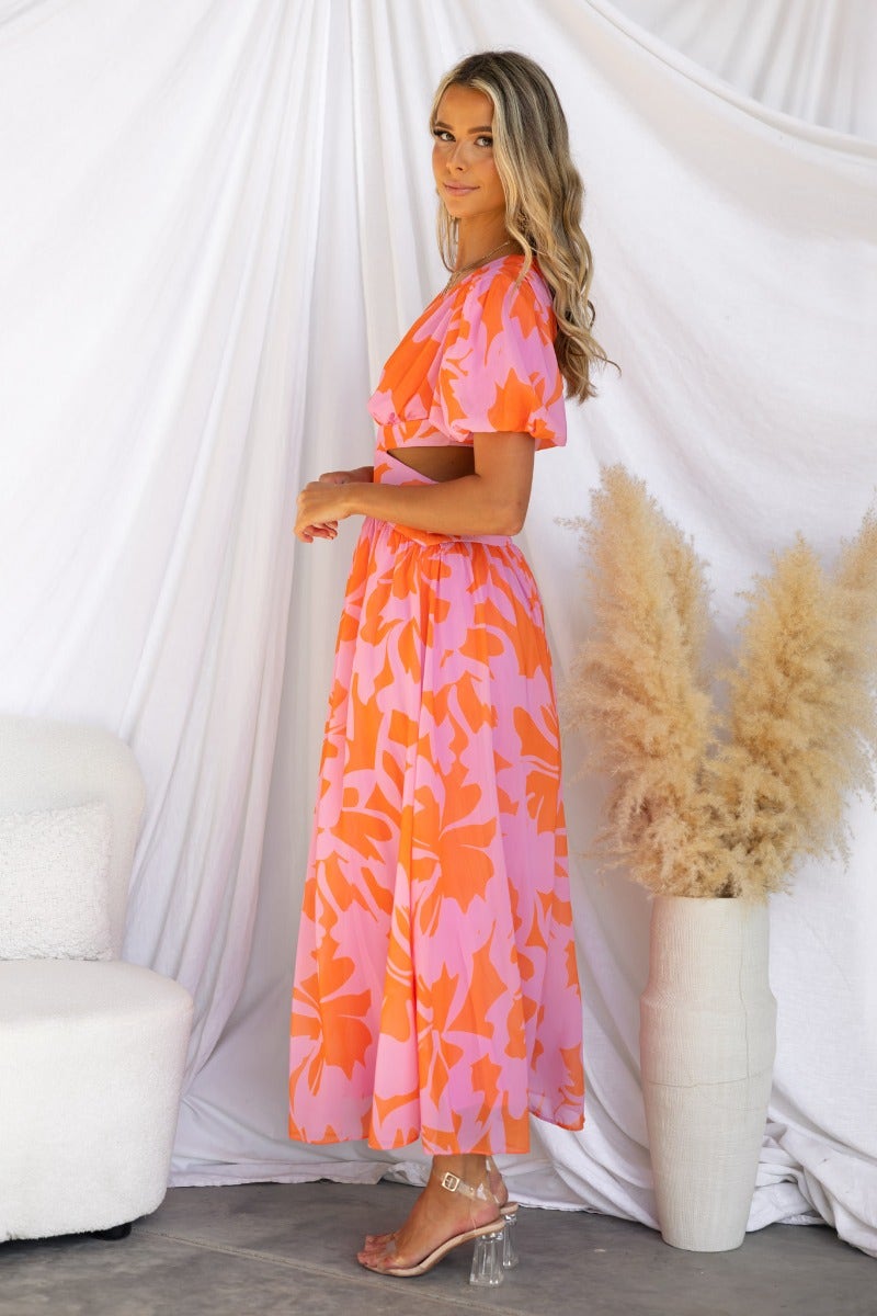 Marleen Maxi Dress in floral pink and orange print, featuring V-neckline and cut-out waist, model wears size XS.
