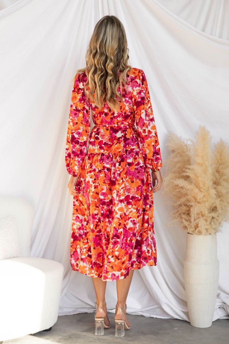 Back view of a floral print midi dress in vibrant colors with elastic cuffs and a high neckline.