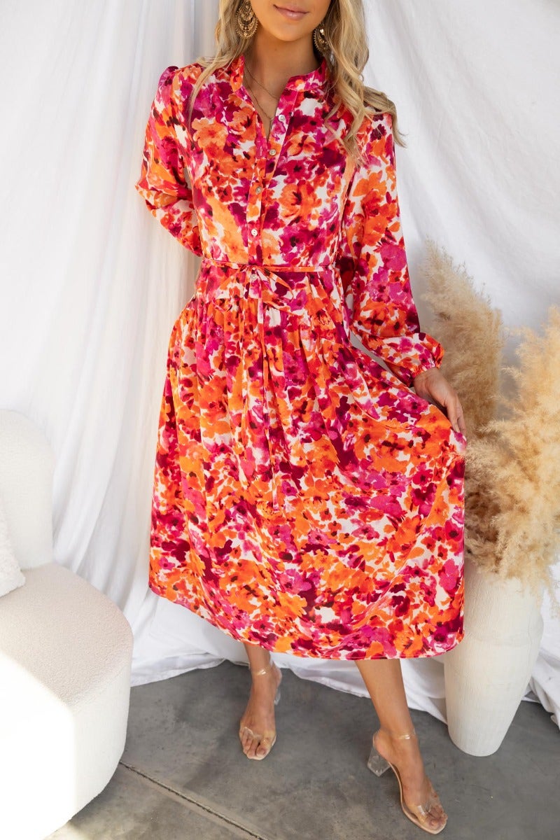 Andreas Midi Dress in vibrant floral print, featuring button-up bust and elastic cuff sleeves, worn by model.