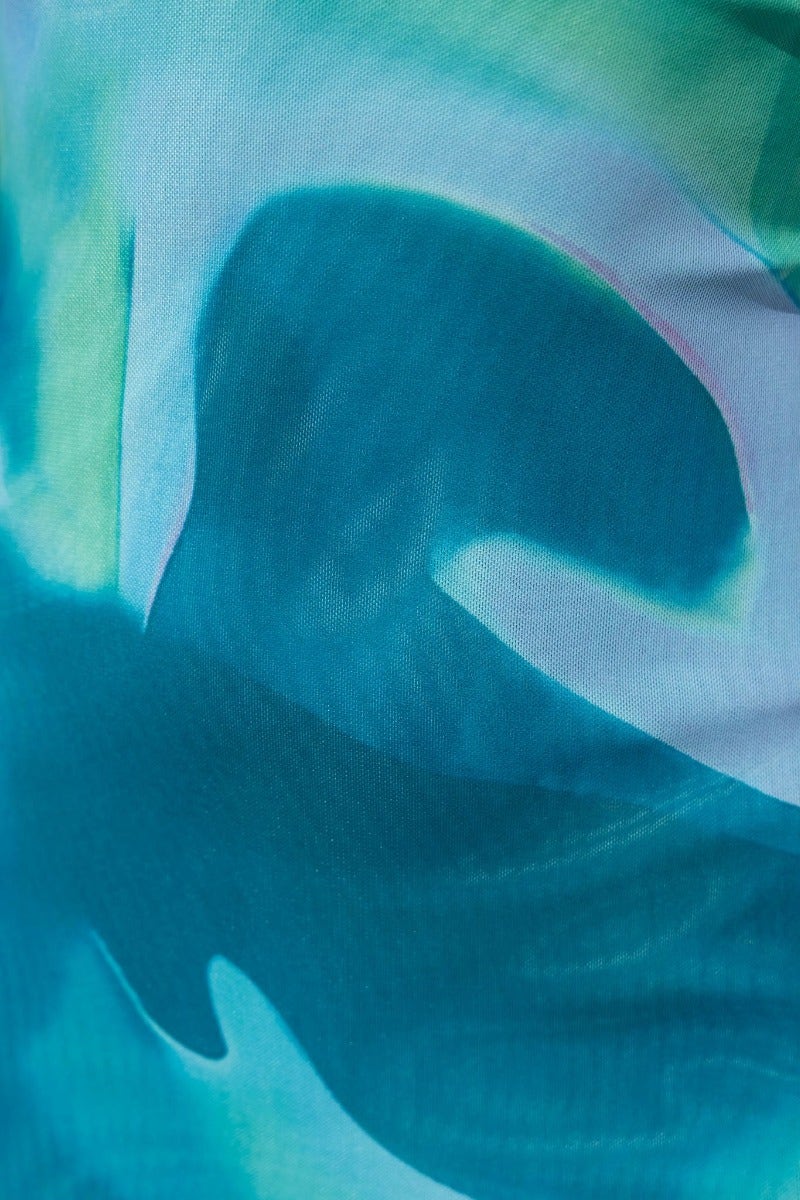 Close-up of teal and green abstract fabric pattern, ideal for fashion design and textiles.