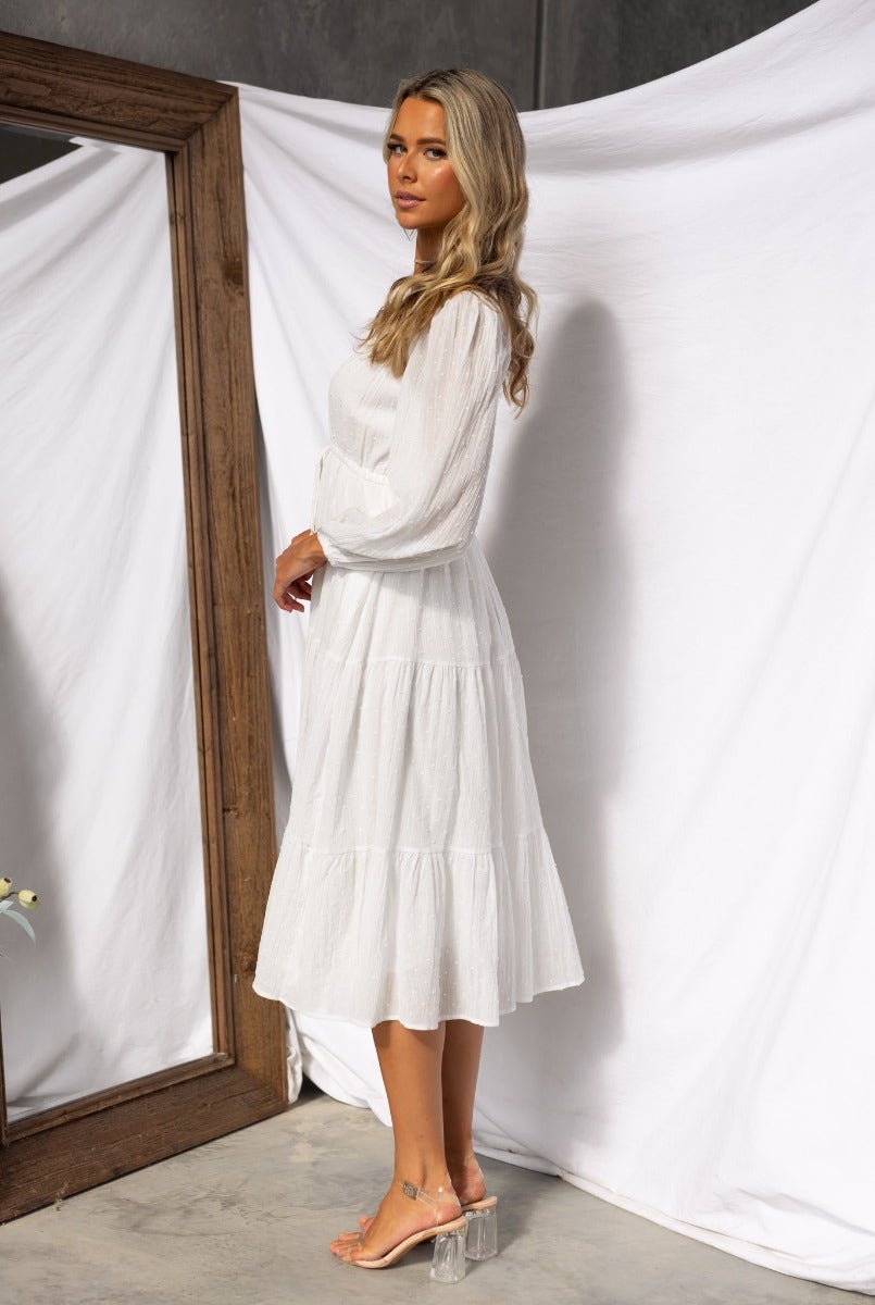 Rayna Midi Dress in white, featuring textured cotton, button-up bust, and flowy tiered skirt, styled with clear heels.