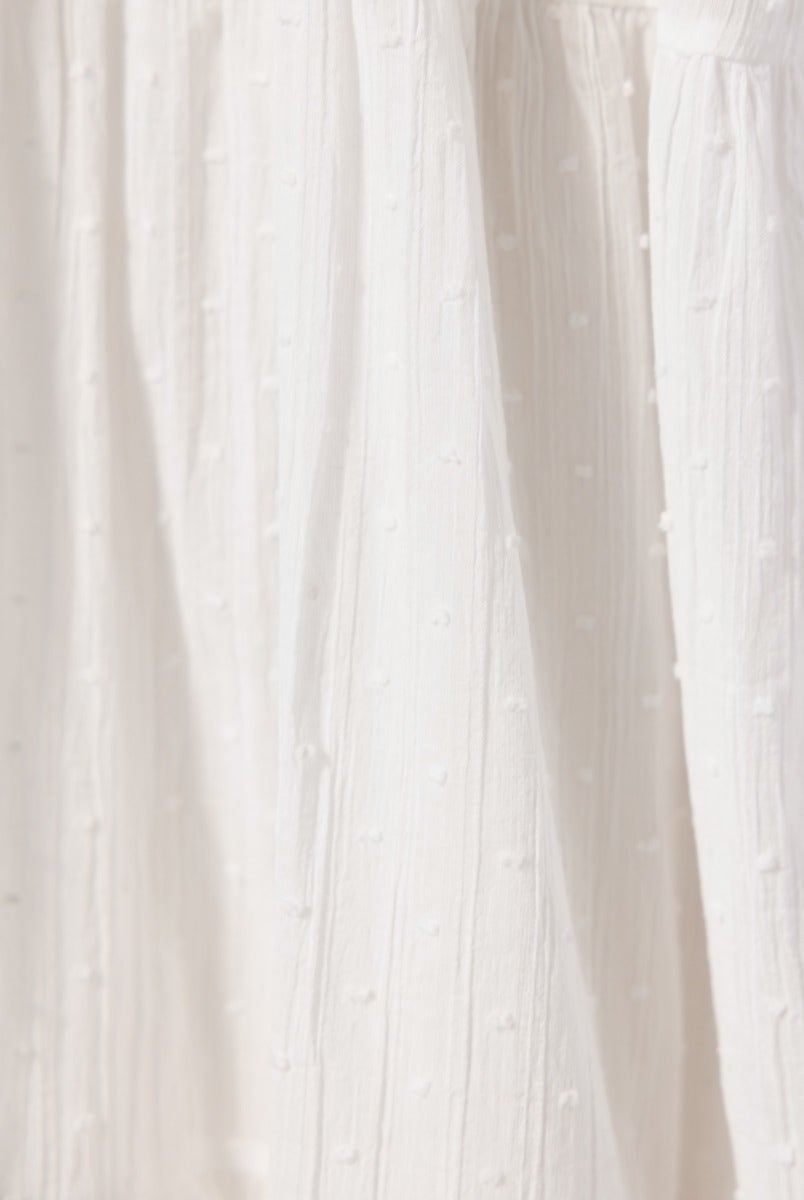 Close-up of textured white cotton fabric with small raised dots, showcasing the details of a Rayna Midi Dress.