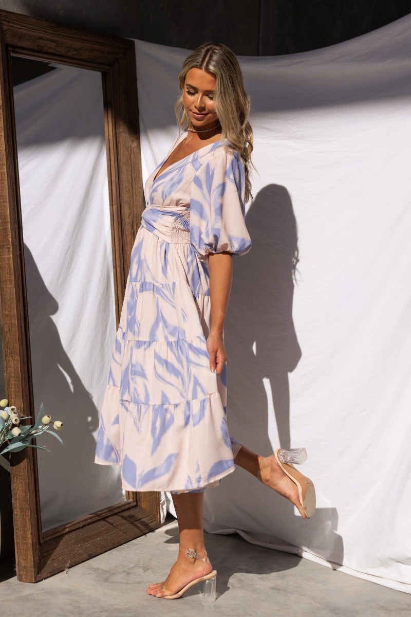 Model wearing Orchi Midi Dress with V-neckline and puff sleeves, showcasing the elegant cotton design in a soft color palette.