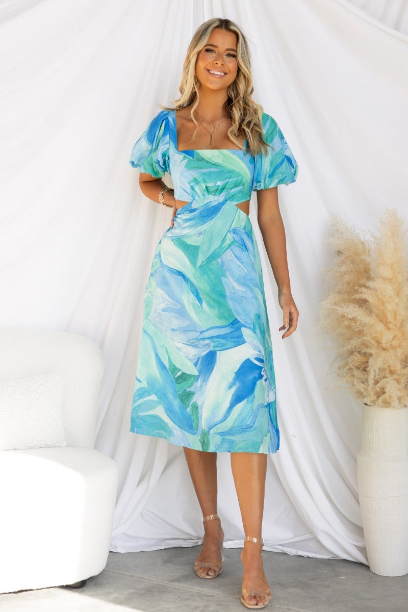 Ayla Midi Dress featuring a square neckline, cut-out waist, and elastic sleeves in a vibrant blue-green pattern.
