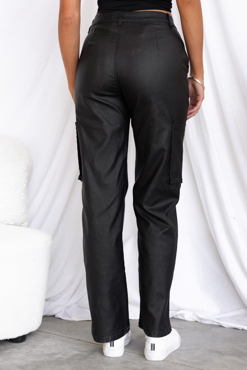 Back view of Deniz faux leather cargo pants with wide legs and pockets, styled with a casual top.