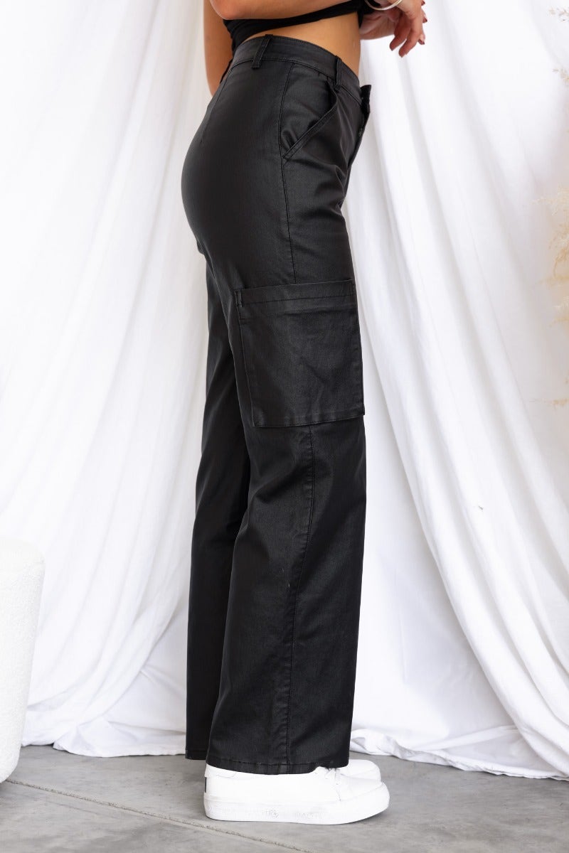Side view of Deniz Cargo Pants in faux leather, featuring wide legs and pockets, styled with a crop top.