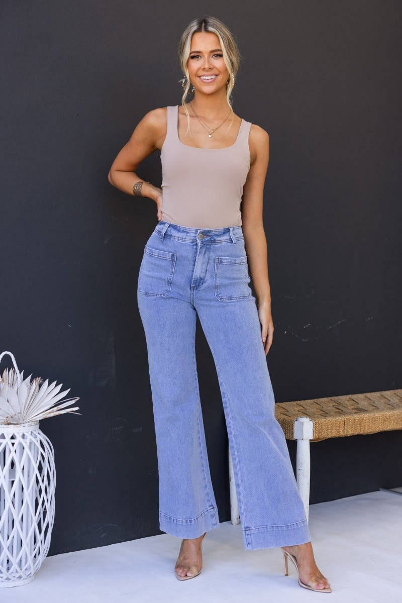 Model wearing light blue Lane Jeans with mid-high waist fit, styled with a beige top and heels.