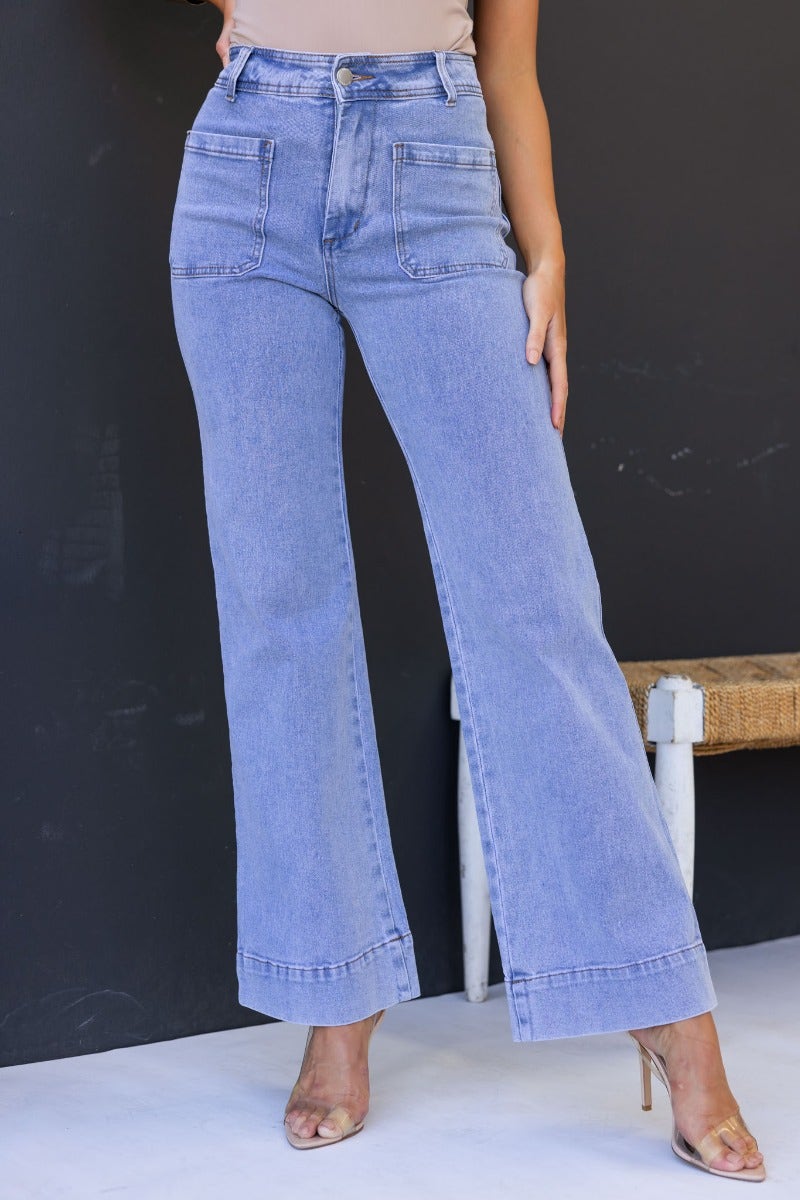 Light wash denim Lane Jeans with mid-high waist and pockets, styled with heels against a black background.