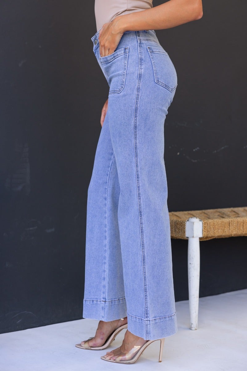 Model wearing Lane Jeans in light blue with mid-high waist and flared legs, showcasing front and back pockets.