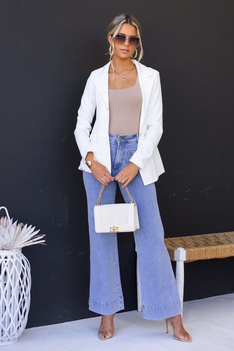 Model wearing the Edin Blazer with faux pockets, button-up front, styled with wide-leg jeans and sunglasses.