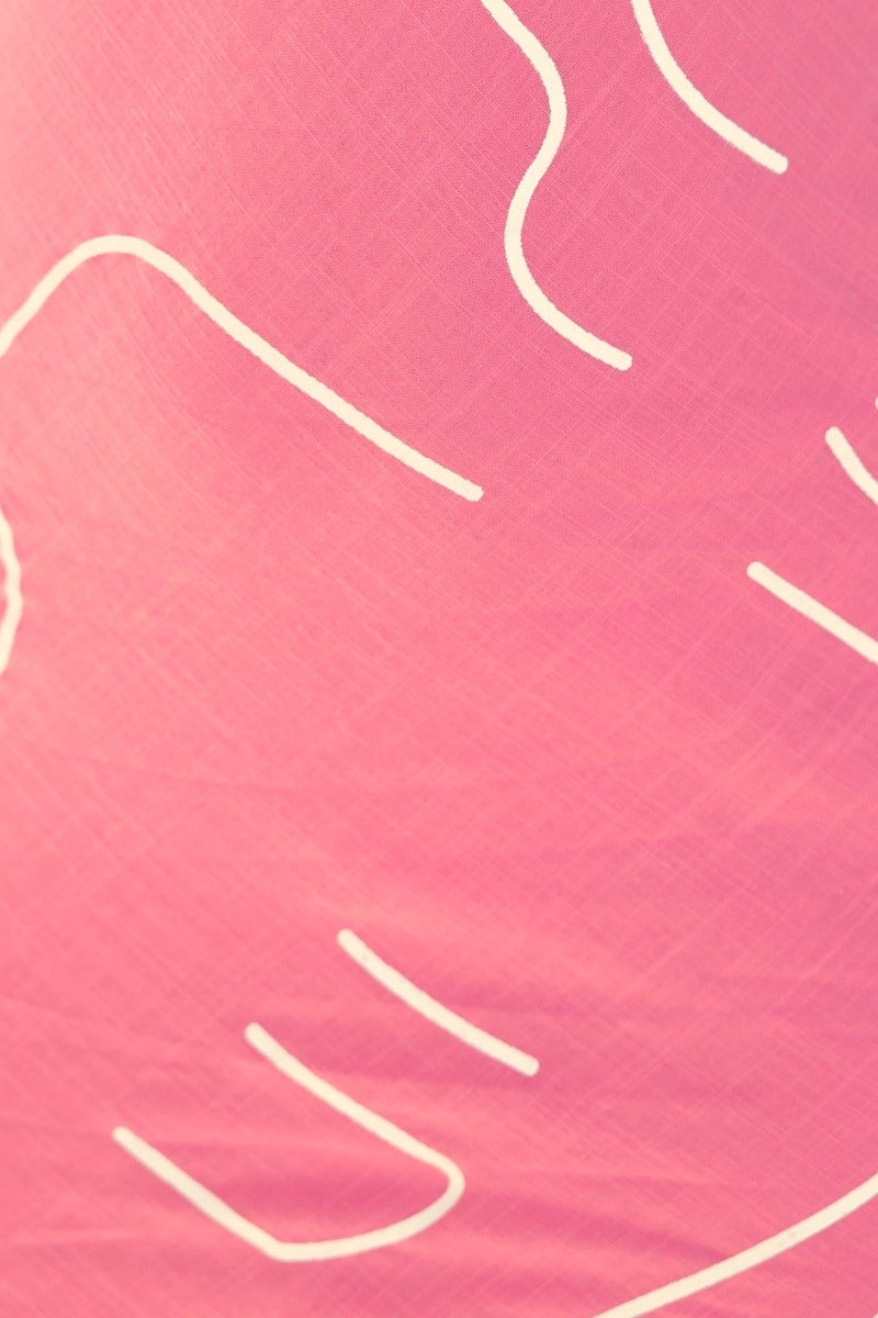 Close-up of pink fabric with white abstract line patterns, showcasing texture and design.