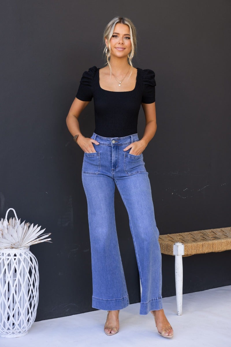 Model wearing Lane Jeans, mid-high waist denim with front and back pockets, styled with a black top.