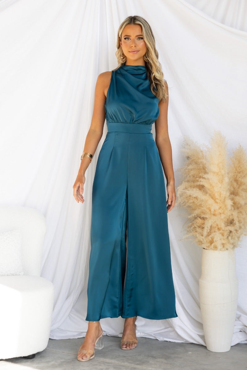 Elegant satin Elyssa jumpsuit featuring a high neckline, tied back, and wide legs, modeled by a woman.