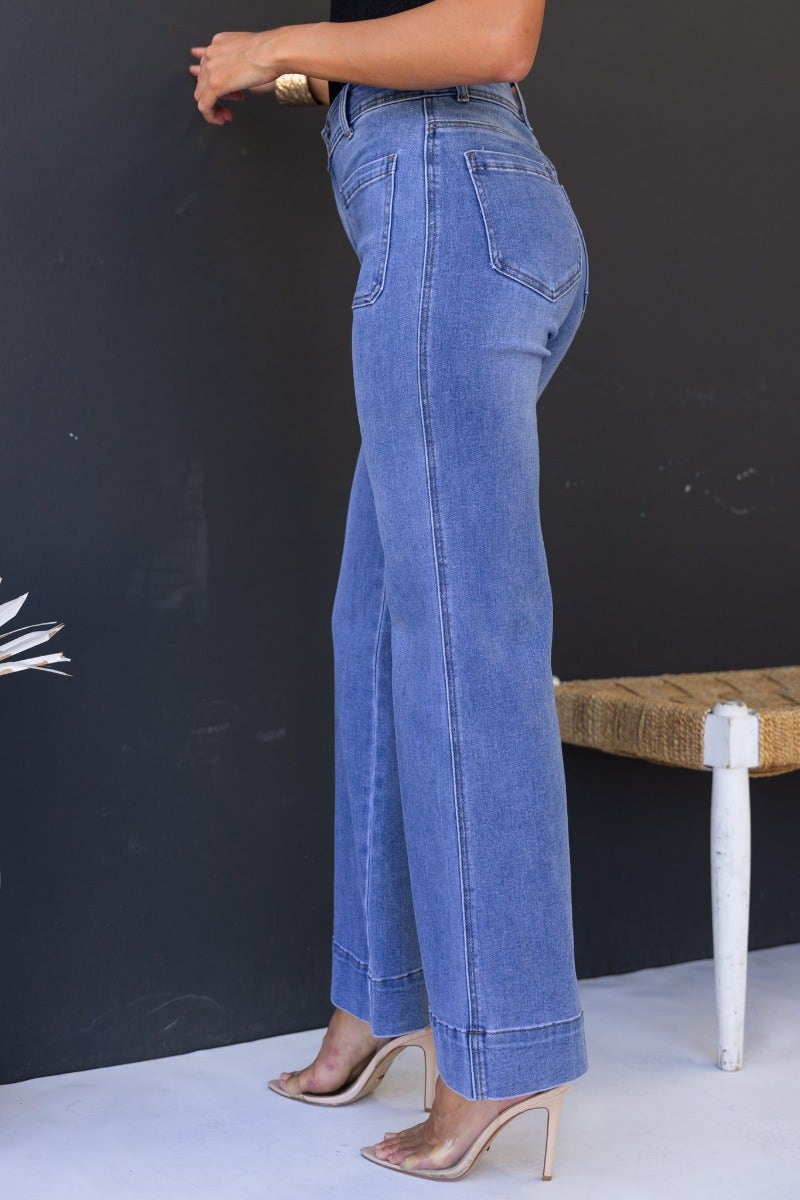 Side view of Lane Jeans in mid-high waist fit, showcasing stretch denim and pockets, styled with heels.