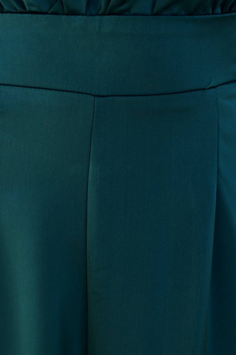 Close-up of Elyssa Jumpsuit fabric showing smooth texture and wide leg design in deep green color.